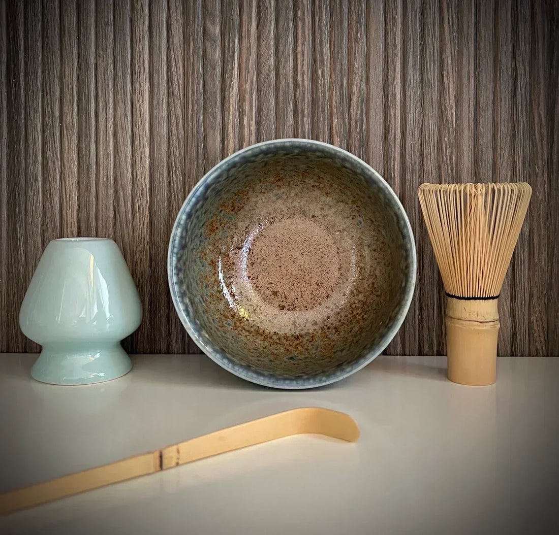 Matcha set met beige matcha kom met zachtblauwe tinten, inclusief bamboe klopper, bamboelepel en lichtblauwe bamboe lepel.