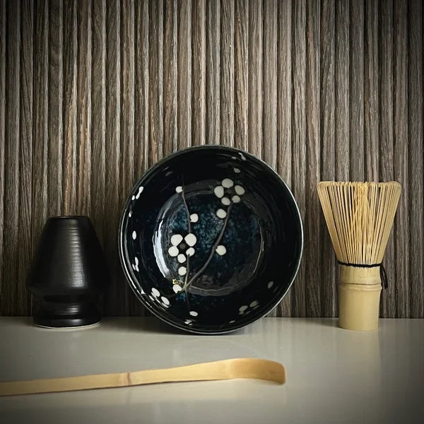 Matcha set met donkerblauwe matcha kom met bloesemtakken, inclusief bamboelepel, bamboe matcha klopper en zwarte whiskhouder. 