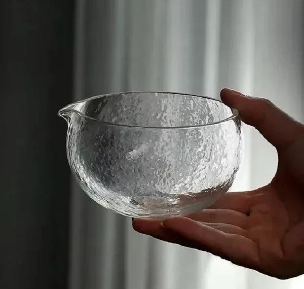 Hand met glazen matcha kom van borosilicaat glas.