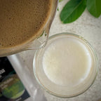 Een glas opgeschuimde melk, de tuit van een glazen matcha kom gevuld met hojicha latte.