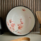 Binnenkant van een matcha kom van keramiek met oudroze bloesemtakken en antracietgrijze buitenkant.