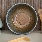 Binnenkant van een beige matcha kom van keramiek met blauw-groene rand.