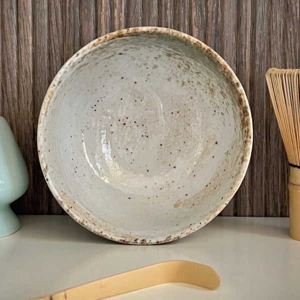 Binnenkant van een ecru matcha kom van keramiek met groen-bruine tinten.