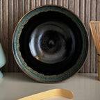 Binnenkant van een geglazuurde zwarte matcha kom van keramiek met groen-blauwe rand.