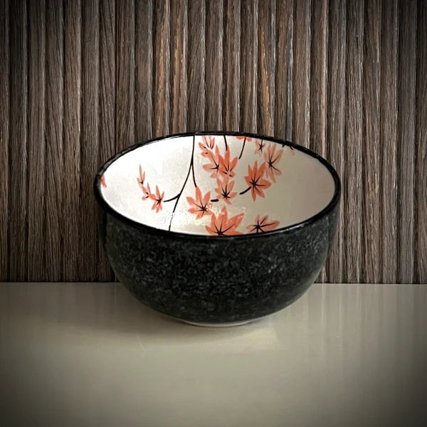 Voorkant van een matcha kom van keramiek met oudroze bloesemtakken en antracietgrijze buitenkant.