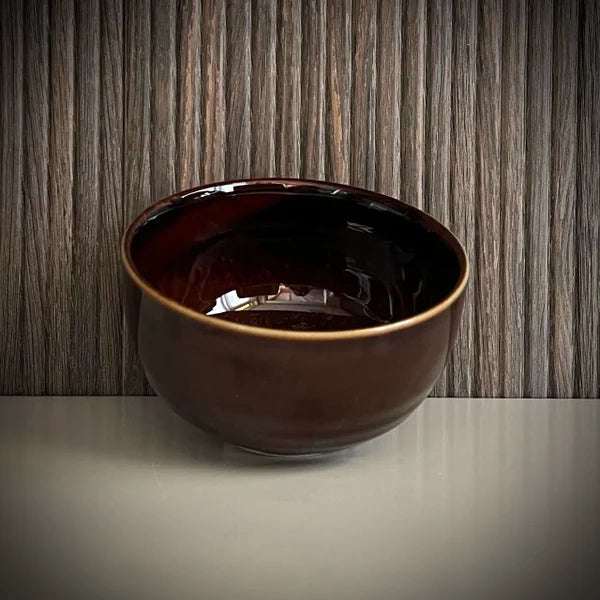 Voorkant van een geglazuurde bordeaux matcha kom van keramiek. 