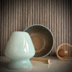 Matcha set met beige matcha kom met zachtblauwe tinten, inclusief whisk, bamboelepel, bamboe matcha klopper en lichtblauwe whiskhouder op de voorgrond.