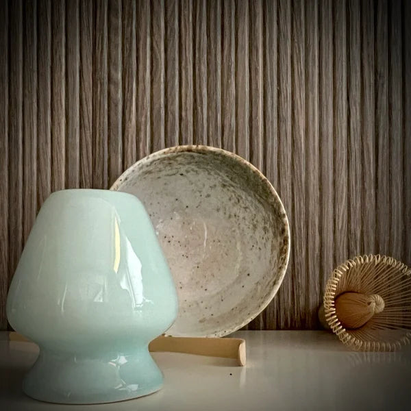 Matcha set met ecru matcha kom, inclusief bamboelepel, bamboe matcha klopper en lichtblauwe whiskhouder op de voorgrond.