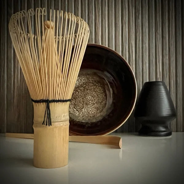 Matcha set met bordeaux matcha kom, inclusief whisk, bamboelepel, zwarte whiskhouder en bamboe matcha klopper op de voorgrond.