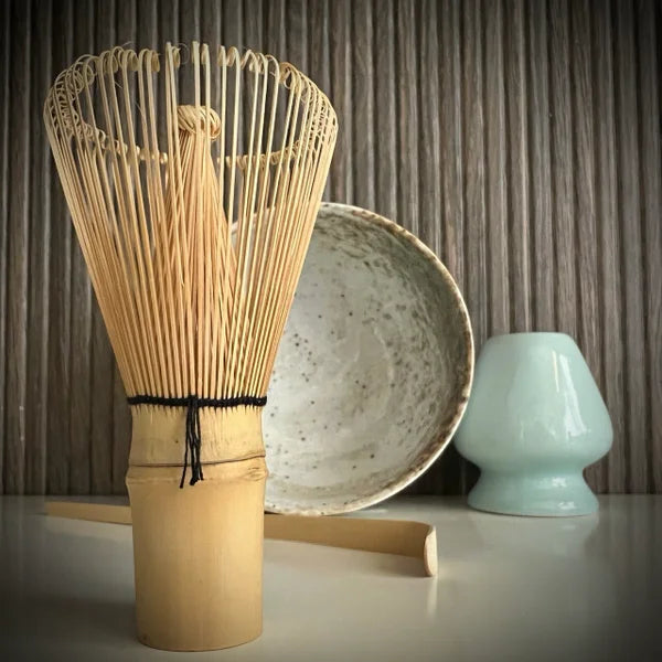Matcha set met ecru matcha kom, inclusief bamboelepel, lichtblauwe whiskhouder en bamboe matcha klopper op voorgrond.