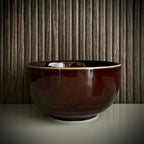 Voorzijde van een geglazuurde bordeaux matcha kom van keramiek. 