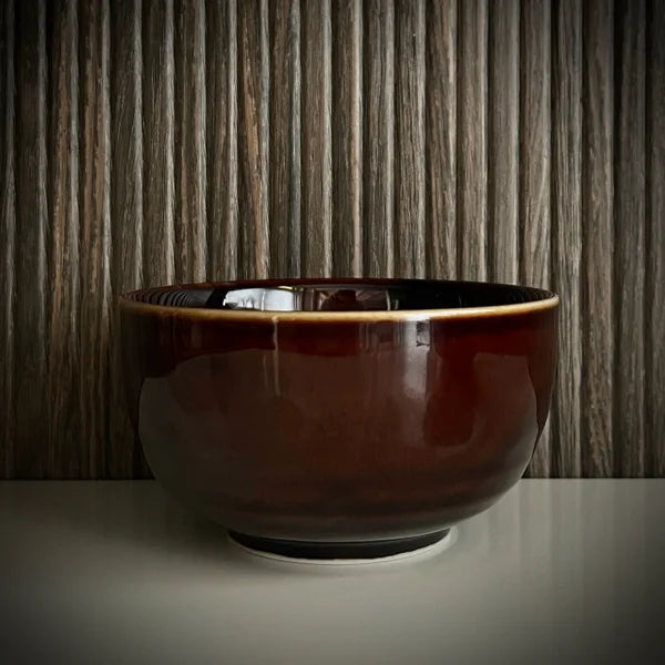 Voorzijde van een geglazuurde bordeaux matcha kom van keramiek. 