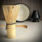 Matcha set met lichtblauwe matcha kom, inclusief bamboelepel, zwarte whiskhouder en bamboe matcha klopper op de voorgrond.