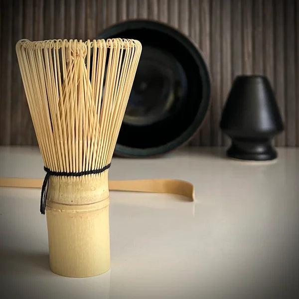 Matcha set met zwarte matcha kom, inclusief bamboelepel, zwarte whiskhouder en bamboe matcha klopper op voorgrond.