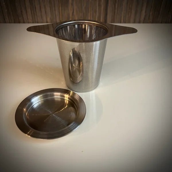 Roestvrij stalen theefilter met vleugels en roestvrijstalen lekschaaltje.