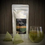 Hersluitbaar zakje' Matcha-Iri Genmaicha' uit Japan van The Matcha Man, een glas met thee en twee theezakjes.