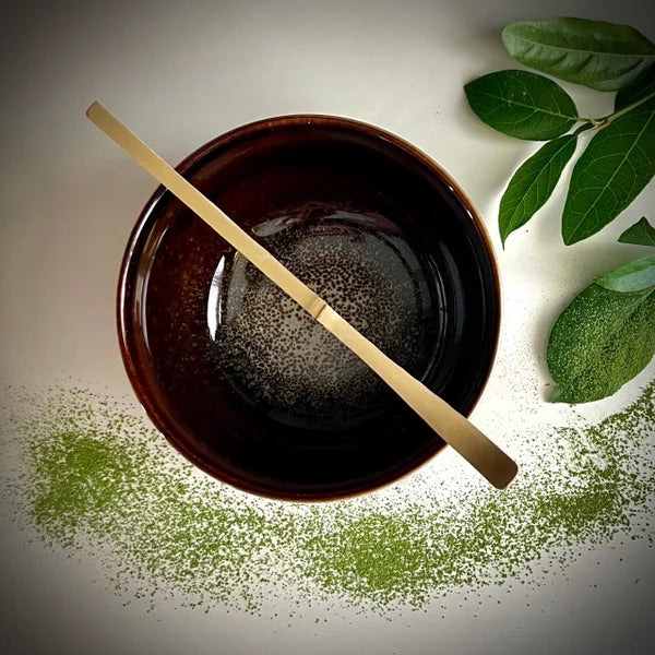 Bovenaanzicht van een bordeaux matcha kom en een bamboelepel.