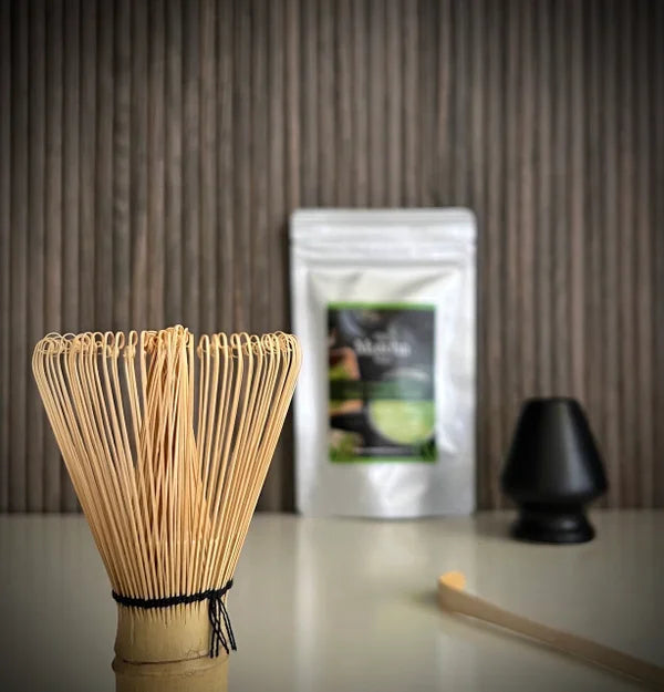Japanse matcha set  van The Matcha Man, bestaande uit hersluitbaar zakje 'Ceremonial Hgh Grade Matcha' (25 gram), een zwarte whiskhouder, een bamboelepel en een bamboe matchaklopper op voorgrond.