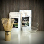 Matcha set van The Matcha Man , bestaande uit hersluitbaar zakje 'Matcha for Latte Vanilla' en hersluitbaar zakje 'Matcha for Latte Pure', een bamboe matchaklopper en een glazen matcha kom met tuit.