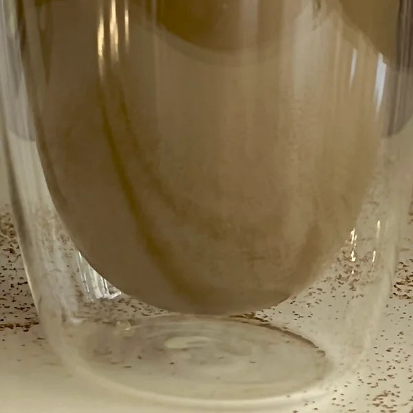 Close up van een dubbelwandig theeglas gevuld met hojicha.