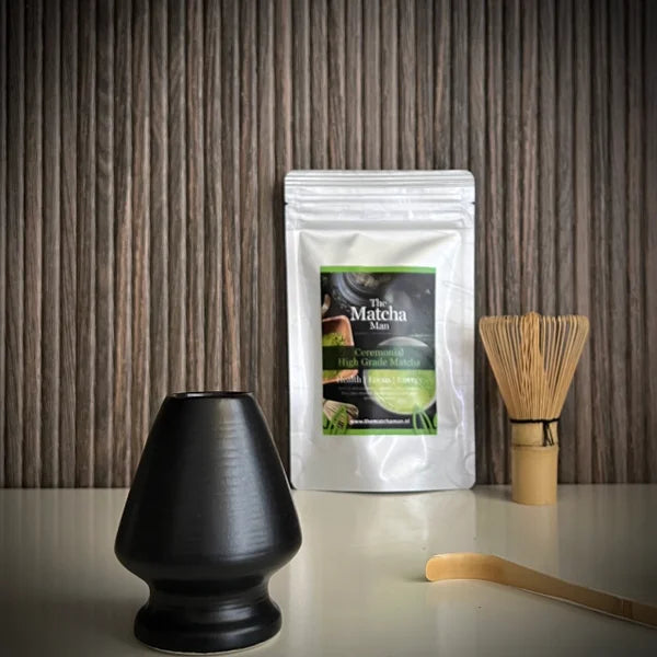 Japanse matcha set  van The Matcha Man, bestaande uit hersluitbaar zakje 'Ceremonial Hgh Grade Matcha' (25 gram),  een bamboe matchaklopper, een bamboelepel en een zwarte whiskhouder op voorgrond.