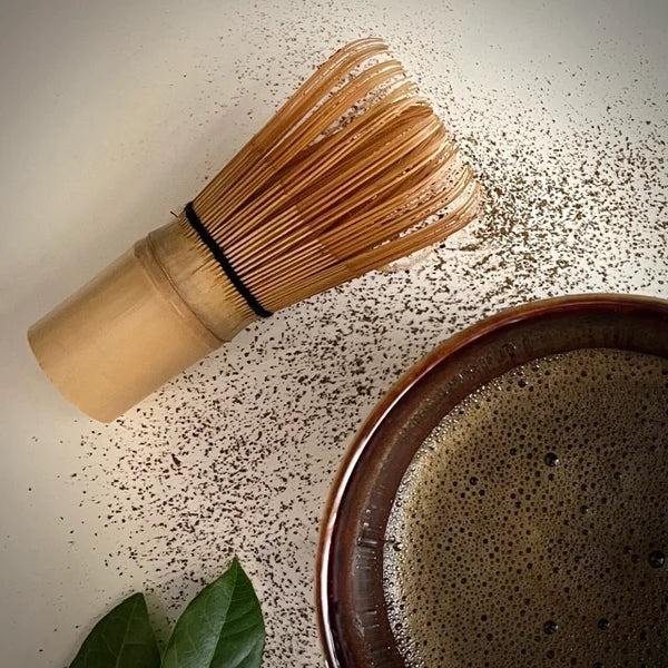 Japanse bamboe matcha klopper met 100 pongs liggend en gedeelte bordeaux matcha kom met hojicha.